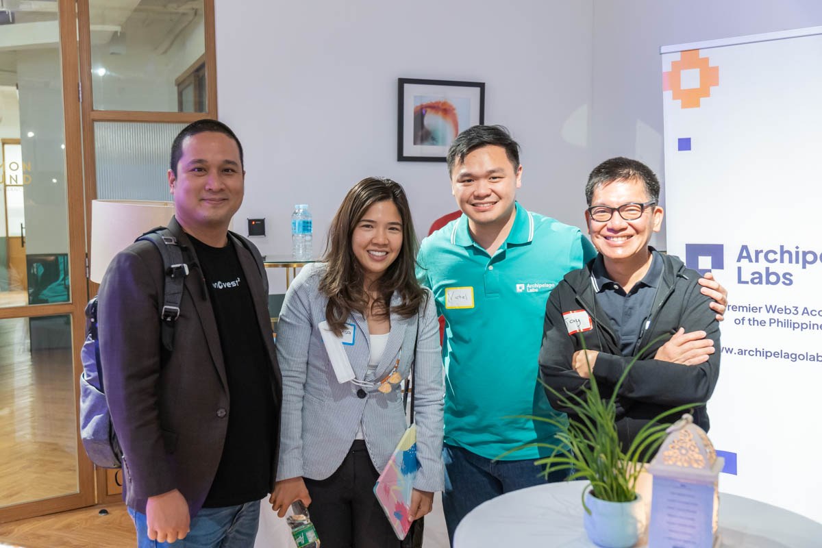 Four guests posing beside the Archipelago Labs event signage